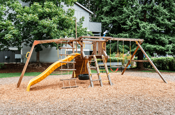 a swing set with a yellow slide in a backyard